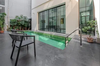 a swimming pool in a building with a table and chairs at Sukumvit Pool Villa 5BR 5-7min-walk to Thonglor Sky train in Khlong Toei