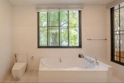 a white bathroom with a tub and a toilet at Sukumvit Pool Villa 5BR 5-7min-walk to Thonglor Sky train in Khlong Toei