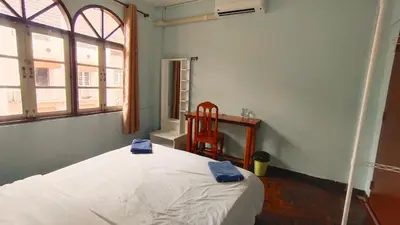 a bedroom with a bed and a chair and a window at Stay Hostel in Bangkok