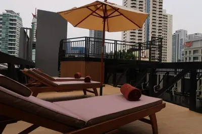 a balcony with chairs and an umbrella on a building at Syama Suite Sukhumvit 20 in Bangkok