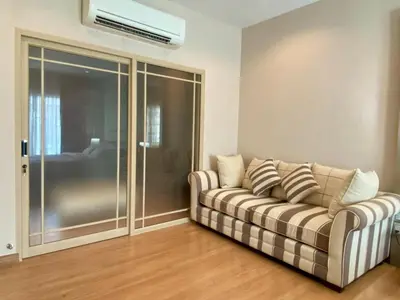 a living room with a couch and a sliding glass door at Cozy home near impact arena in Nonthaburi