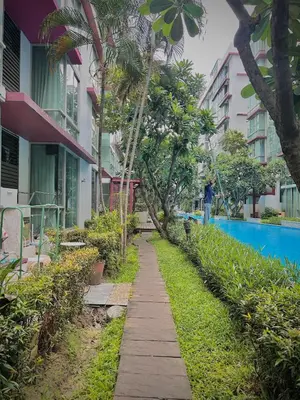 a walkway next to a building with palm trees at Condo In Bangkok With Pool and Garden in Sathani Ban Hua Mak