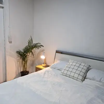 a bedroom with a white bed and a plant at Casita Hostel House Bangkok in Bangkok