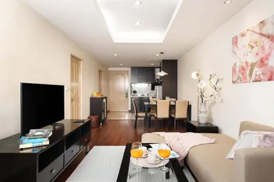 a living room with a couch and a tv at Mystic Haven King Bed Suite with Balcony & City Views in Khlong Toei