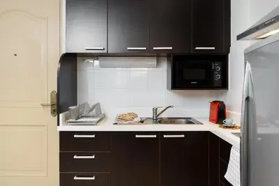 a kitchen with black cabinets and a sink at Jungle Dream King Bed Oasis with Balcony & High-Speed WiFi in Khlong Toei