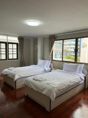 two beds in a bedroom with two windows at Urban Grace in Bangkok