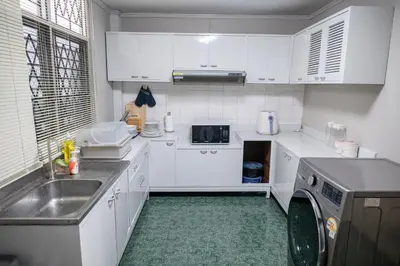 a white kitchen with a sink and a dishwasher at Urban Grace in Bangkok
