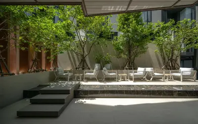 a courtyard with chairs and trees in a building at The Moment in Bangkok