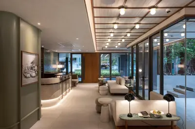 a lobby with chairs and tables and windows at The Moment in Bangkok