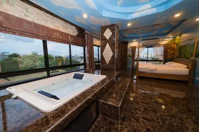 a bathroom with a bath tub and a bedroom at Thongtara House Boutique Srinakarin in Bangkok