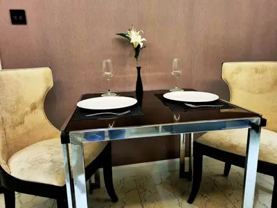 a dining table with two glasses and a vase with a flower at State tower City view Central River Station in Bangkok