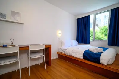 a bedroom with a bed and a desk and a window at Yummy House in Bangkok