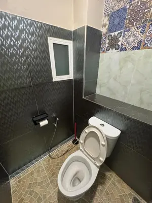 a bathroom with a toilet with a window and tiles at WannaB Hostel in Khlong San