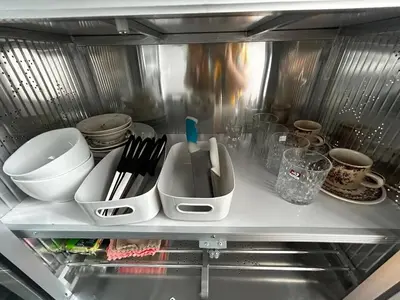 a refrigerator filled with dishes and utensils on a shelf at Comfy1BR at Bangson byBB in Bangkok