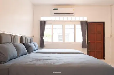 a bedroom with two beds and a window at Nan Square II in Bangkok