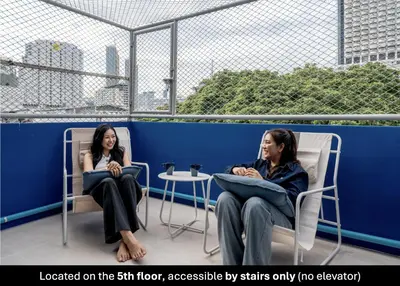 two women sitting in chairs on a balcony at Blue House 191 Hometel in Chinatown