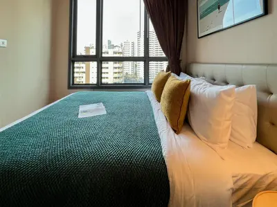 a bedroom with a large bed with a window at Stylish Modern 1BR - Ultra Fast Wifi - BTS Phrom Phong in Bangkok