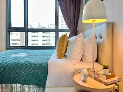 a bedroom with a bed and a table with a lamp at Stylish Modern 1BR - Ultra Fast Wifi - BTS Phrom Phong in Bangkok