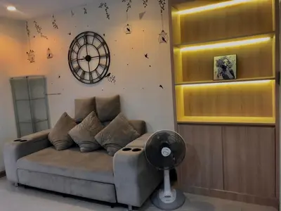 a living room with a couch and a clock on the wall at คอนโดศุภาลัยเวลลิงตัน2 in Bangkok