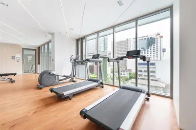 a gym with cardio machines and large windows at The Rich Grand Residence Sukhumvit in Bangkok
