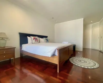 a bedroom with a large bed and a wooden floor at Trinity City View 3BR Spacious Family Silom in Bangkok