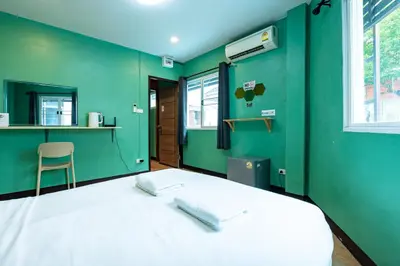 a green room with a bed with two pillows on it at xxGO INN The Giant Swing - เสาชิงช้า in Bangkok