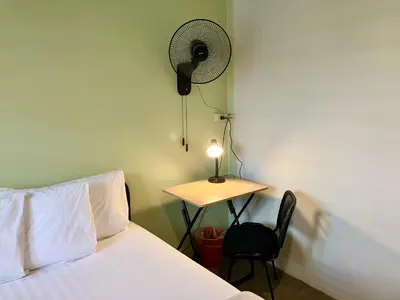 a bedroom with a bed and a desk with a fan at 326 Podtel at The Breakie Bar in Bangkok