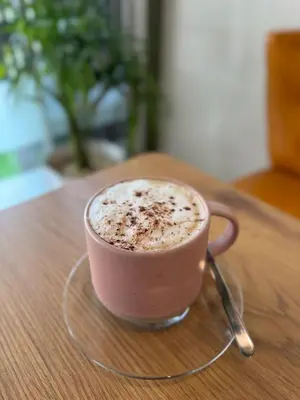 a cup of coffee sitting on a wooden table at 326 Podtel at The Breakie Bar in Bangkok