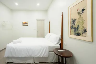 a white bedroom with a bed and a table at XX Hidden Dragon Yaowarat Road in Bangkok