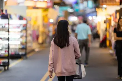 a woman walking down a street in a market at I LOVE BANGKOK - Thai Style Room near Skytrain Asok, T21, and EM District Malls in Bangkok