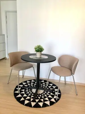 a table with two chairs and a potted plant on a rug at Resort style family room near BTS Bearing in Ban Khlong Samrong