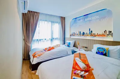 a hotel room with two beds and a poster on the wall at Metro Hotel Phahonyothin 35 in Bangkok