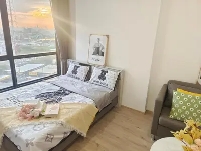 a bedroom with a bed and a chair and a window at The Rich Rama 9 Luxury Condos in Sathani Ban Hua Mak