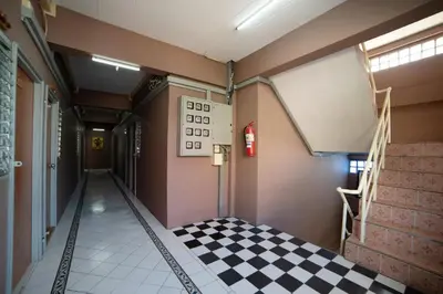 a hallway with a checkered floor in a building at Sukhum Sukhumvit-Onnut Guest House in Amphoe Phra Khanong