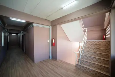 a hallway with stairs in a building with a fire extinguisher at Sukhum Sukhumvit-Onnut Guest House in Amphoe Phra Khanong