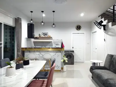 a kitchen and living room with a table and a couch at Hidden Gems Residence in Ban Sala Daeng