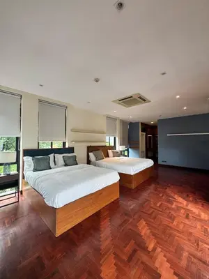 two beds in a large room with wooden floors at Central BKK Luxuxy Pool Villa 4BR in Bangkok