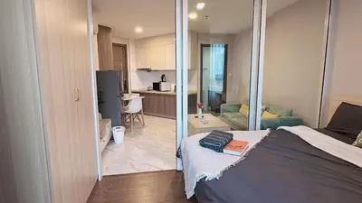 a bedroom with a bed and a living room at Artisan Ratchada Prime Studio Condos in Bangkok