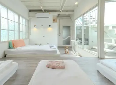 a large room with two beds and a bathroom at Old Town Heritage Lofts Bangkok in Bangkok