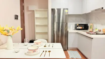 a kitchen with a table with plates and flowers on it at Artisan Ratchada Huge 1BR Condos in Bangkok