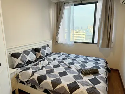 a bedroom with a bed with a checkered blanket and a window at Artisan Ratchada Spacious 2BR Condos in Bangkok
