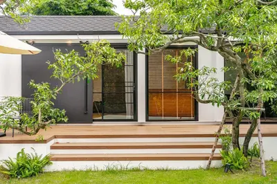a home with a wooden staircase leading up to a house at The Lodge Bangkok Poolvilla in Sathani Khlong Tan