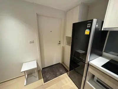 a small kitchen with a refrigerator and a door at Paradise condo-perfect location in Bangkok