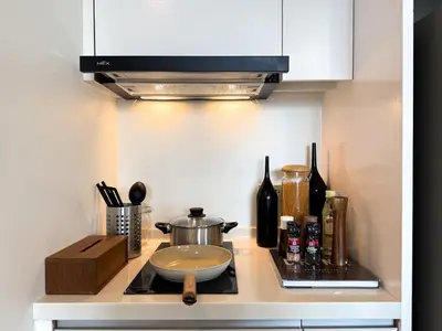 a kitchen counter with a stove top with a microwave at Spacious City 69 SQM - Fast WiFi - BTS Chong Nonsi in Bangkok