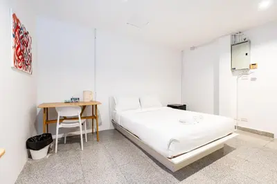 a white bedroom with a bed and a table at xx Mitr INN Sukhumvit 2 - BTS Nana มิตร อินน์ สุขุมวิทซอย 2 บีทีเอส นานา in Bangkok
