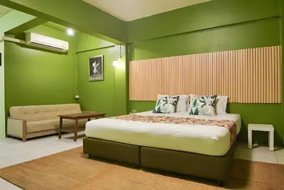 a bedroom with a large bed and a chair at GO INN The Grand Palace - โกอินน์ MRT สามยอด in Bangkok