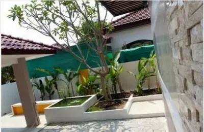 a potted tree in a white planter next to a building at Privacy House in Ban Bang Phai