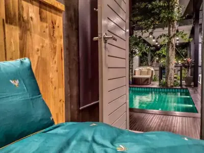 a door leading to a swimming pool with a bed next to it at Garden and pool Villa bangkok in Bang O