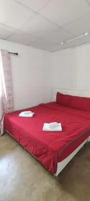 a red bed with two white towels on top of it at Double Room-C102 in Bangkok