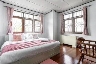 a bedroom with a bed and two windows at 110 House 4Bedroom in Ban Zong Katiam